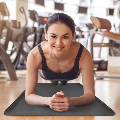 A woman performing a plank on a gray Fitnessmat.